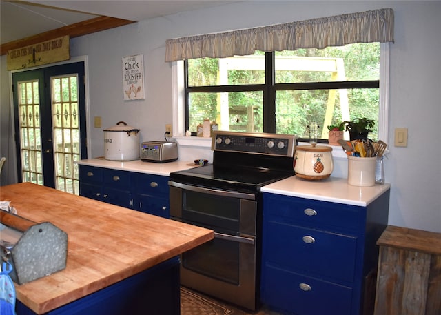 kitchen featuring blue cabinetry, range with two ovens, french doors, and wood counters