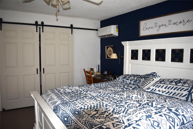 bedroom featuring ceiling fan, a closet, a wall unit AC, and a barn door