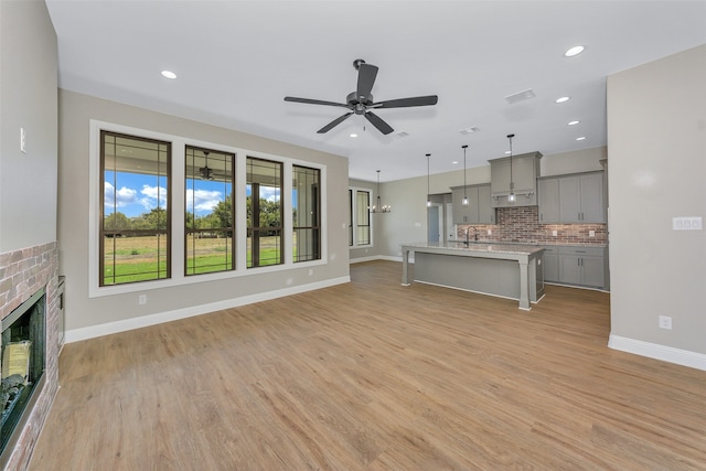 unfurnished living room featuring a brick fireplace, ceiling fan, and light hardwood / wood-style floors