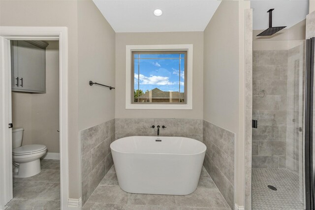 bathroom with tile walls, toilet, and independent shower and bath