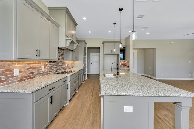 kitchen with sink, decorative light fixtures, decorative backsplash, and light hardwood / wood-style floors