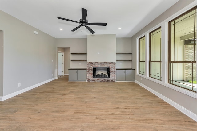 unfurnished living room with light wood-type flooring, ceiling fan, and a fireplace