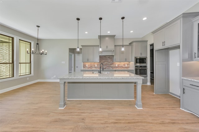 kitchen featuring light wood-type flooring, a kitchen bar, sink, light stone countertops, and appliances with stainless steel finishes