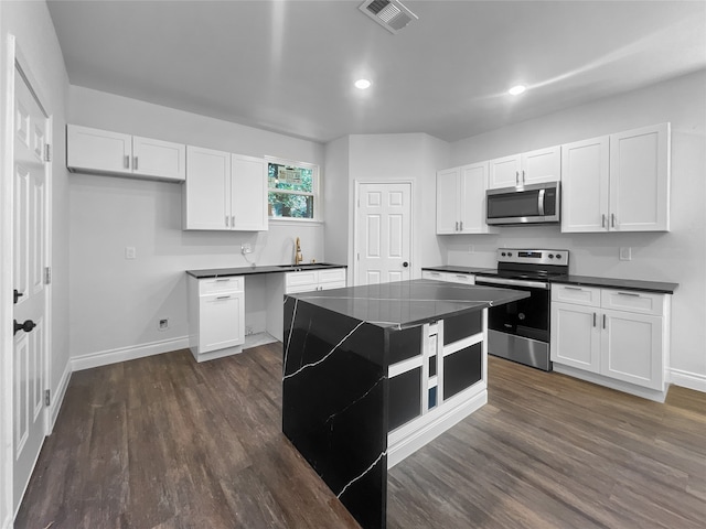 kitchen featuring stainless steel appliances, dark hardwood / wood-style flooring, a center island, sink, and white cabinets