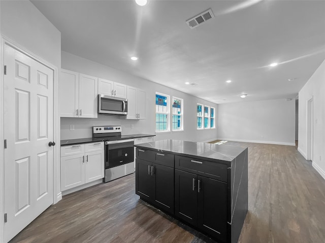 kitchen with a center island, dark wood-type flooring, stainless steel appliances, and white cabinets