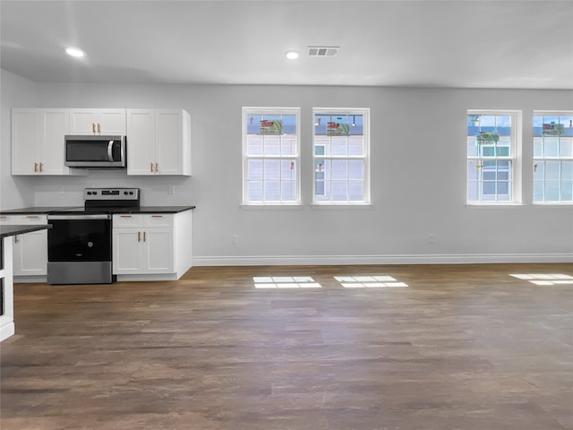 kitchen with dark wood-type flooring, a wealth of natural light, stainless steel appliances, and white cabinets