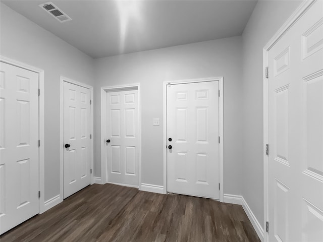 unfurnished bedroom with dark hardwood / wood-style flooring and multiple closets