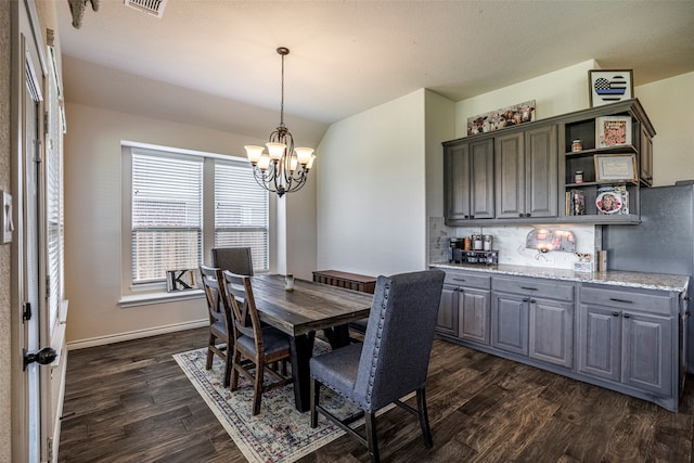 dining space with a textured ceiling, dark wood-type flooring, and an inviting chandelier