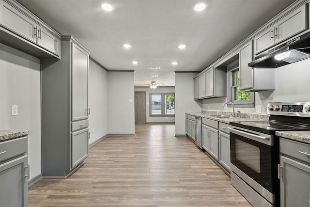 kitchen featuring appliances with stainless steel finishes, a sink, under cabinet range hood, and gray cabinetry