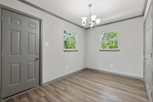 unfurnished room featuring baseboards, crown molding, an inviting chandelier, and wood finished floors