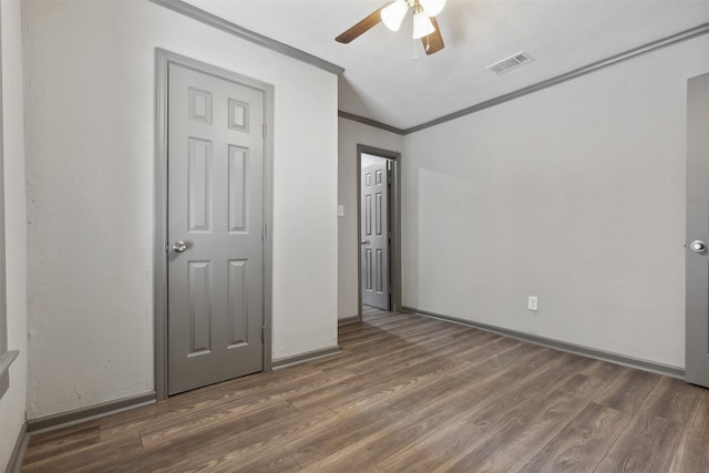 unfurnished bedroom featuring crown molding, visible vents, ceiling fan, wood finished floors, and baseboards