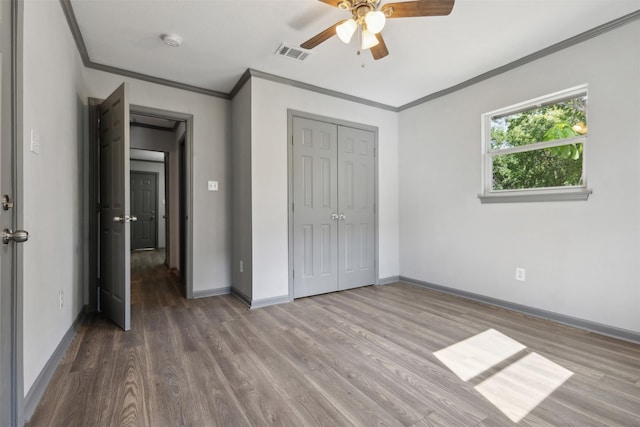 unfurnished bedroom featuring baseboards, crown molding, visible vents, and wood finished floors