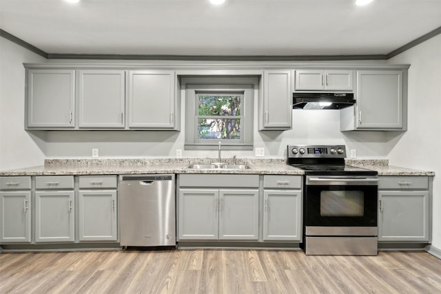 kitchen with under cabinet range hood, gray cabinetry, a sink, ornamental molding, and appliances with stainless steel finishes