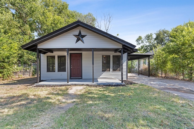 bungalow-style home featuring covered porch, a carport, a front yard, and driveway