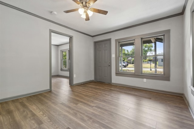 spare room with baseboards, ornamental molding, ceiling fan, and wood finished floors