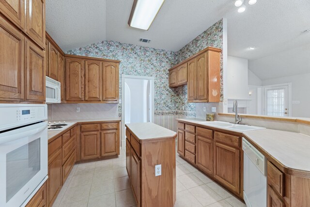 kitchen with white appliances, a kitchen island, sink, vaulted ceiling, and light tile patterned flooring