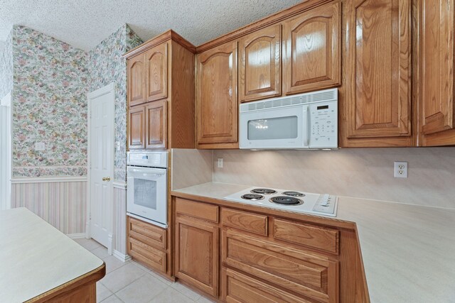 kitchen with white appliances, light tile patterned floors, and a textured ceiling