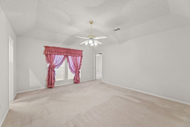 empty room with ceiling fan, light carpet, and a textured ceiling