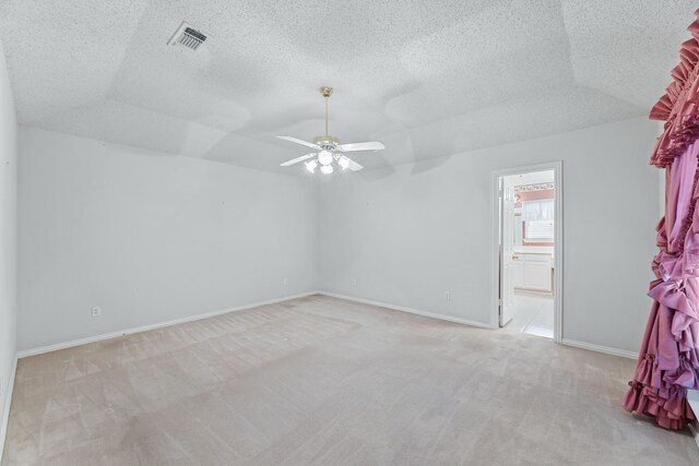 carpeted empty room featuring lofted ceiling, ceiling fan, and a textured ceiling