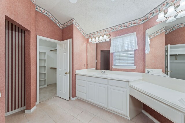 bathroom with vanity, a textured ceiling, vaulted ceiling, and tile patterned flooring