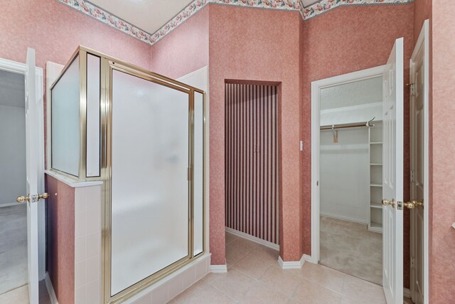 bathroom with a shower with door, tile patterned floors, and a textured ceiling