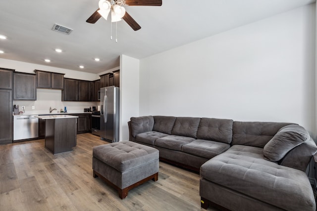 living room featuring light wood-type flooring, sink, and ceiling fan