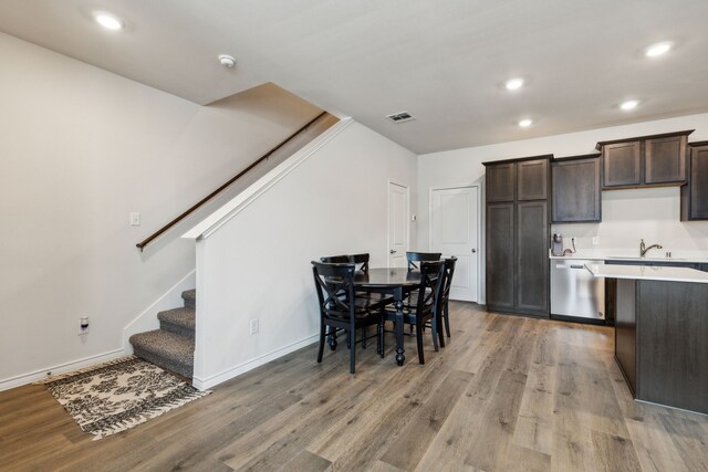 kitchen featuring stainless steel dishwasher, sink, hardwood / wood-style floors, and dark brown cabinets