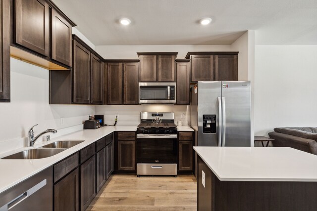 kitchen with light wood-type flooring, dark brown cabinets, stainless steel appliances, and sink