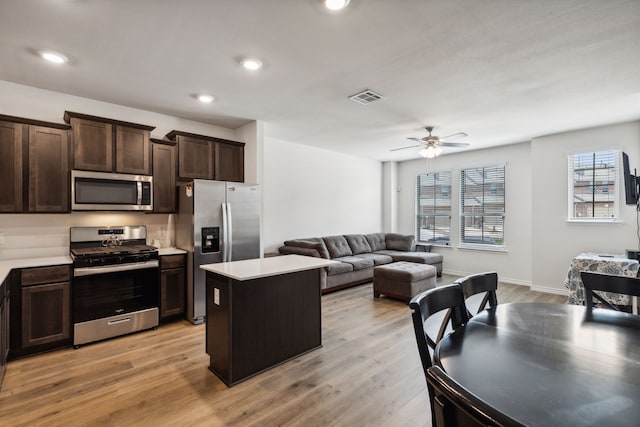 kitchen with a kitchen island, dark brown cabinets, light hardwood / wood-style floors, stainless steel appliances, and ceiling fan