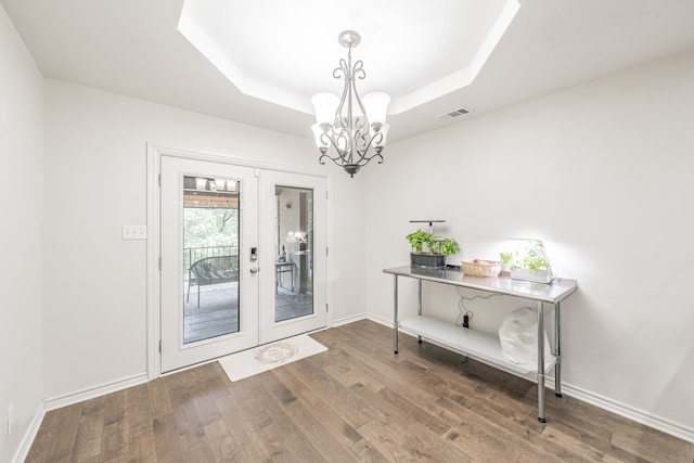 entryway featuring wood finished floors, visible vents, french doors, a raised ceiling, and an inviting chandelier