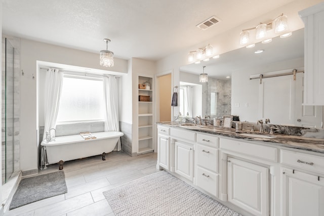 full bathroom featuring vanity, a freestanding tub, a shower stall, and visible vents