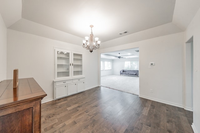 unfurnished dining area with a raised ceiling, visible vents, baseboards, and dark wood-style flooring