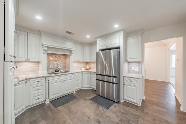 kitchen featuring visible vents, dark wood-style flooring, freestanding refrigerator, white cabinetry, and backsplash