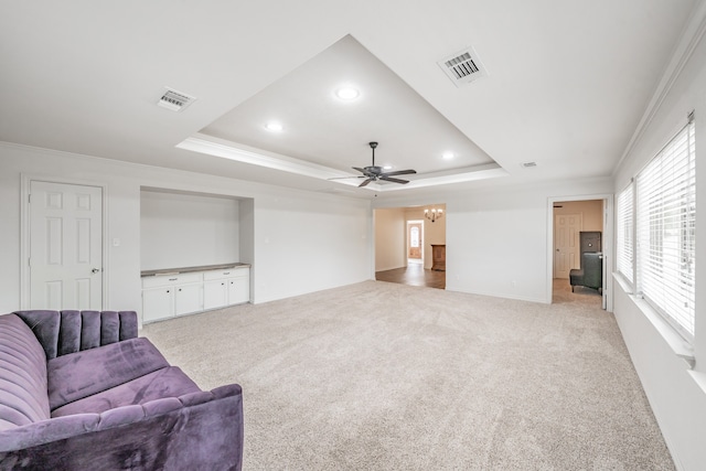 living room featuring a tray ceiling, ceiling fan, light carpet, and ornamental molding