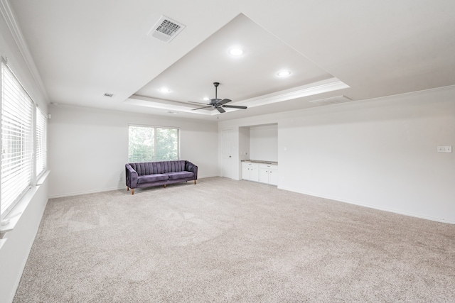 unfurnished room with ceiling fan, a raised ceiling, carpet, and ornamental molding