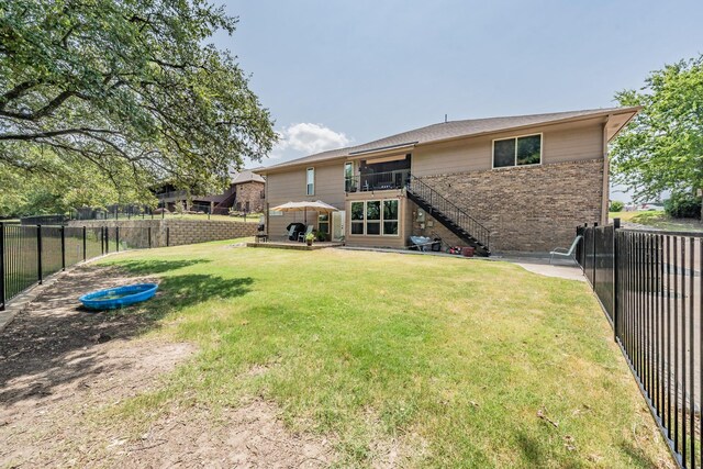 rear view of property with brick siding, a fenced backyard, stairway, and a yard