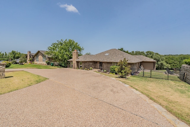 view of front facade featuring brick siding, fence, driveway, a front lawn, and a chimney