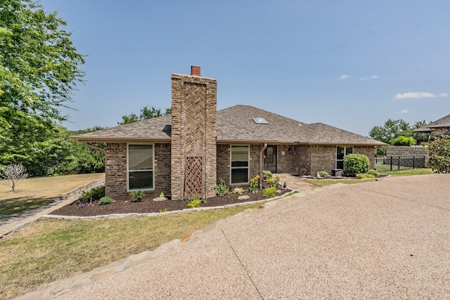 view of front of property featuring roof with shingles, brick siding, a chimney, and fence