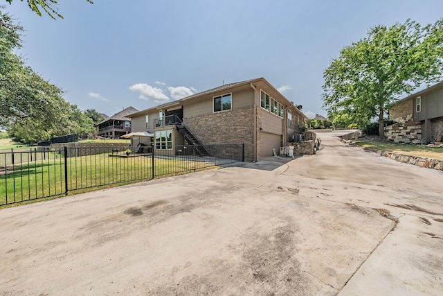 view of side of home with brick siding, fence, driveway, a yard, and stairway