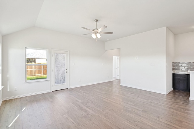 unfurnished living room with ceiling fan, vaulted ceiling, and light hardwood / wood-style flooring