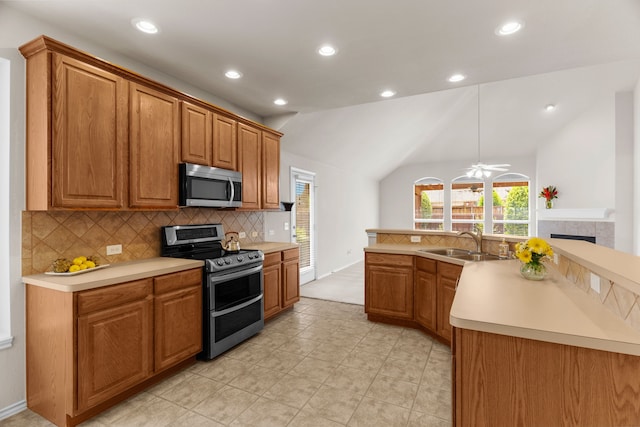 kitchen featuring appliances with stainless steel finishes, vaulted ceiling, sink, decorative light fixtures, and a tiled fireplace