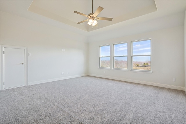 spare room featuring a raised ceiling, ceiling fan, and carpet flooring