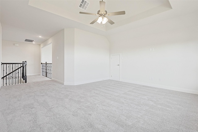 carpeted empty room featuring ceiling fan and a tray ceiling