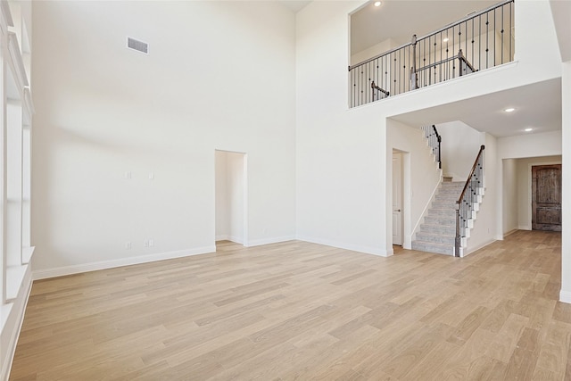 interior space featuring a towering ceiling and light hardwood / wood-style floors