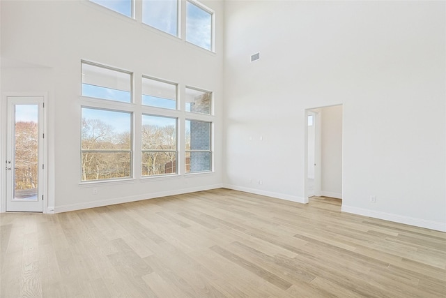 unfurnished living room with a towering ceiling and light wood-type flooring