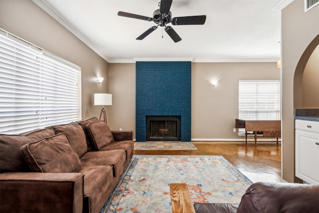 living room featuring crown molding, a fireplace, and ceiling fan