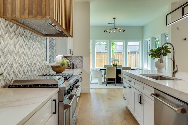 kitchen with light stone countertops, light hardwood / wood-style flooring, appliances with stainless steel finishes, sink, and white cabinets