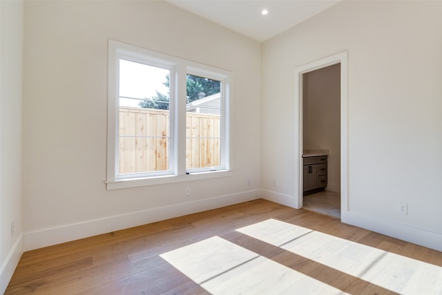 unfurnished bedroom with ensuite bathroom and light hardwood / wood-style floors