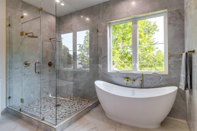 bathroom with a shower stall, a freestanding bath, recessed lighting, marble finish floor, and tile walls