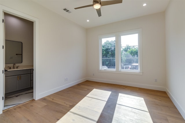 unfurnished bedroom featuring ceiling fan, sink, ensuite bath, and light hardwood / wood-style flooring